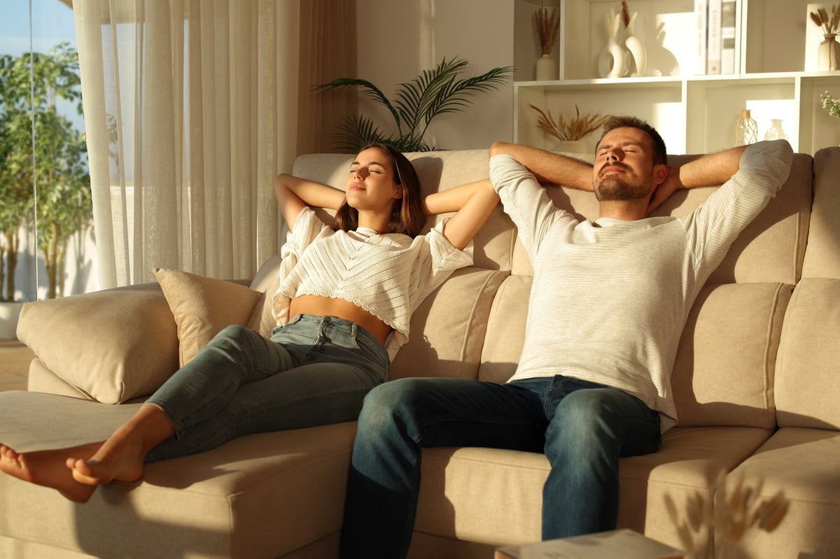 An older couple relaxing together on the sofa of the home they have lived in for decades